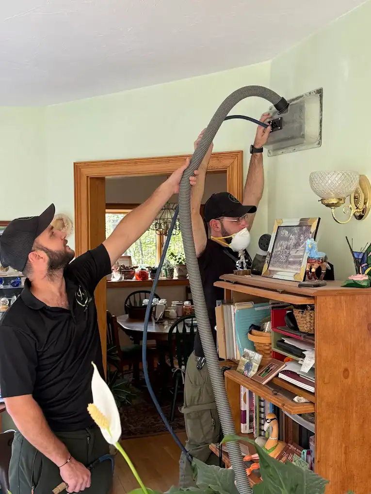 Vacuum hose cleaning wall vent during air duct service