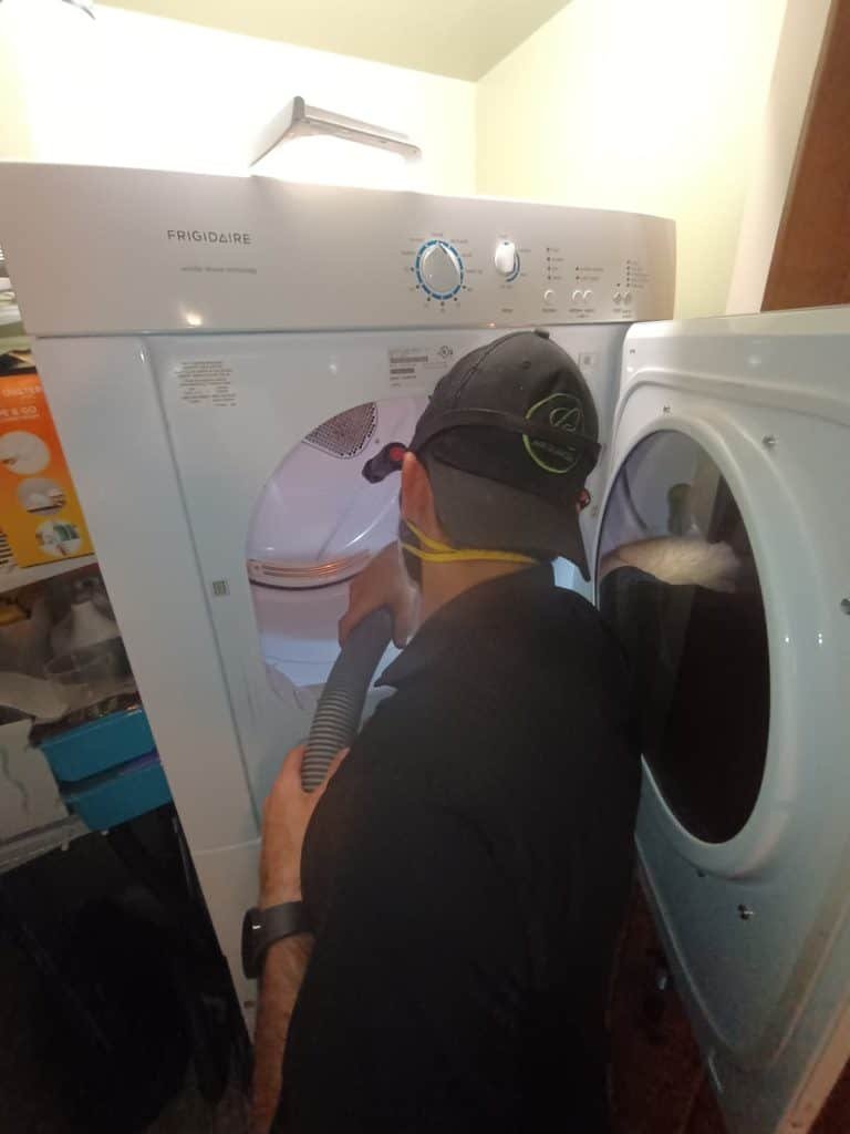 Technician cleaning lint from inside dryer drum