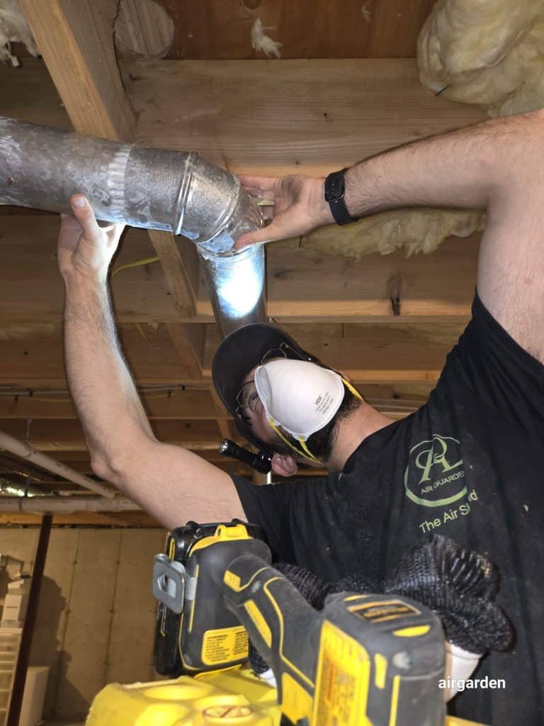 Technician connecting dryer vent duct in crawlspace