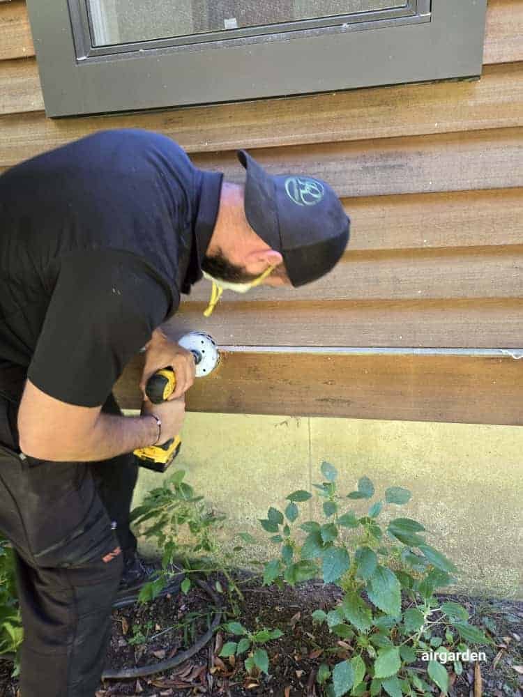Technician installing exterior dryer vent outlet on siding